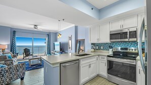 A modern kitchen with white cabinets, a stainless steel refrigerator, and a built-in oven. - Tidewater 706 (Orange Beach)