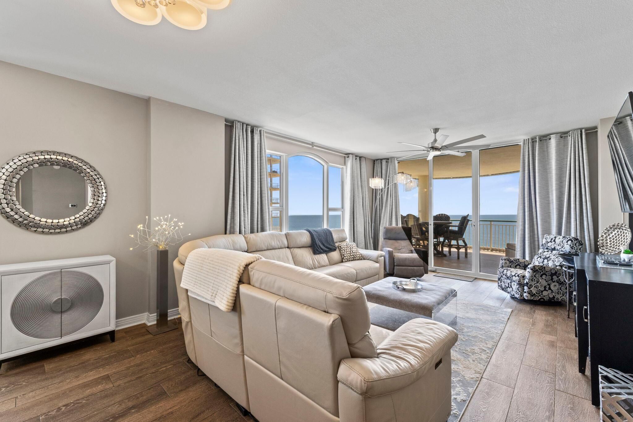 A spacious living room with a beige sectional sofa, a flat-screen TV, and a dining area with a table and chairs.