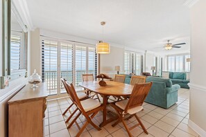A spacious living area with a wooden dining table, teal sofas, and a ceiling fan. - Summer House 1501b (Orange Beach)