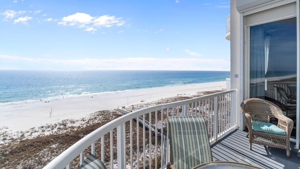 A balcony with wicker furniture overlooking a beach. - Spanish Key 702 (Pensacola)