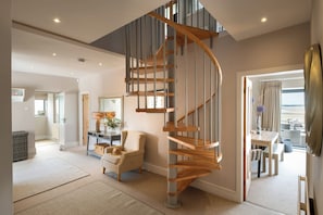 A spacious living area with a modern spiral staircase, a comfortable seating area, and a view to the outside. - Seascape: A fabulous, pet-friendly home with sea views (Rhosneigr)
