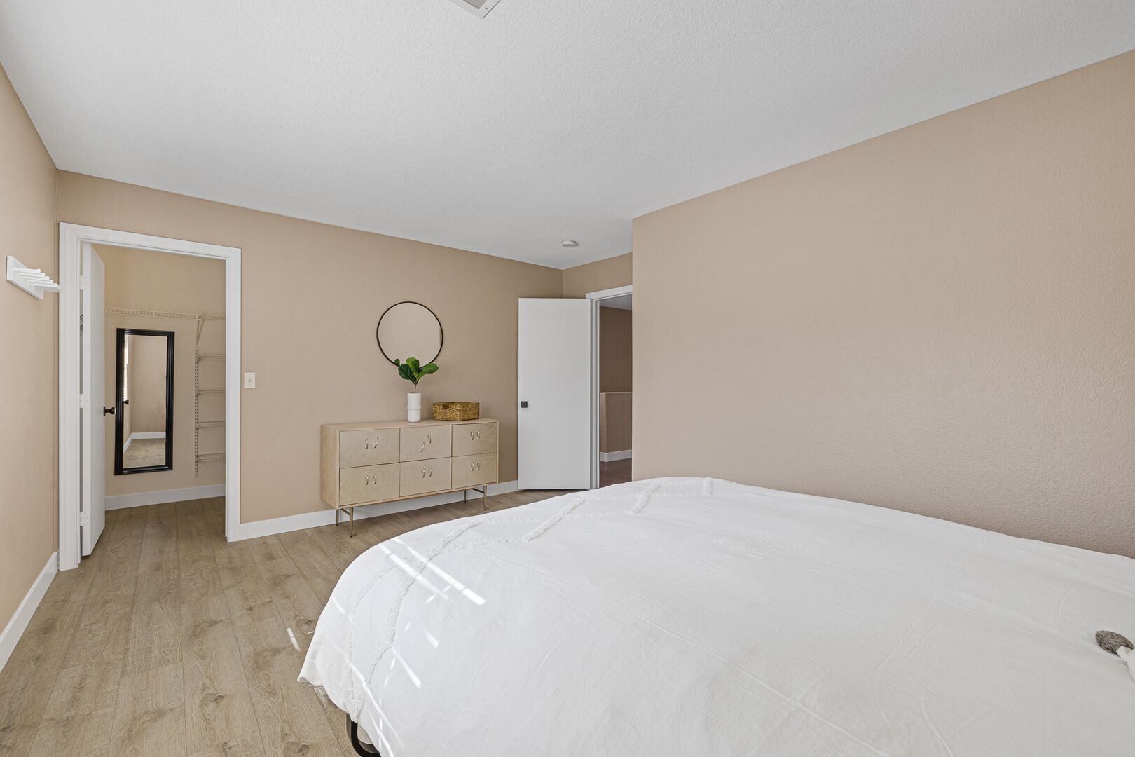 A bedroom with a large bed, a dresser, a mirror, and a wardrobe.