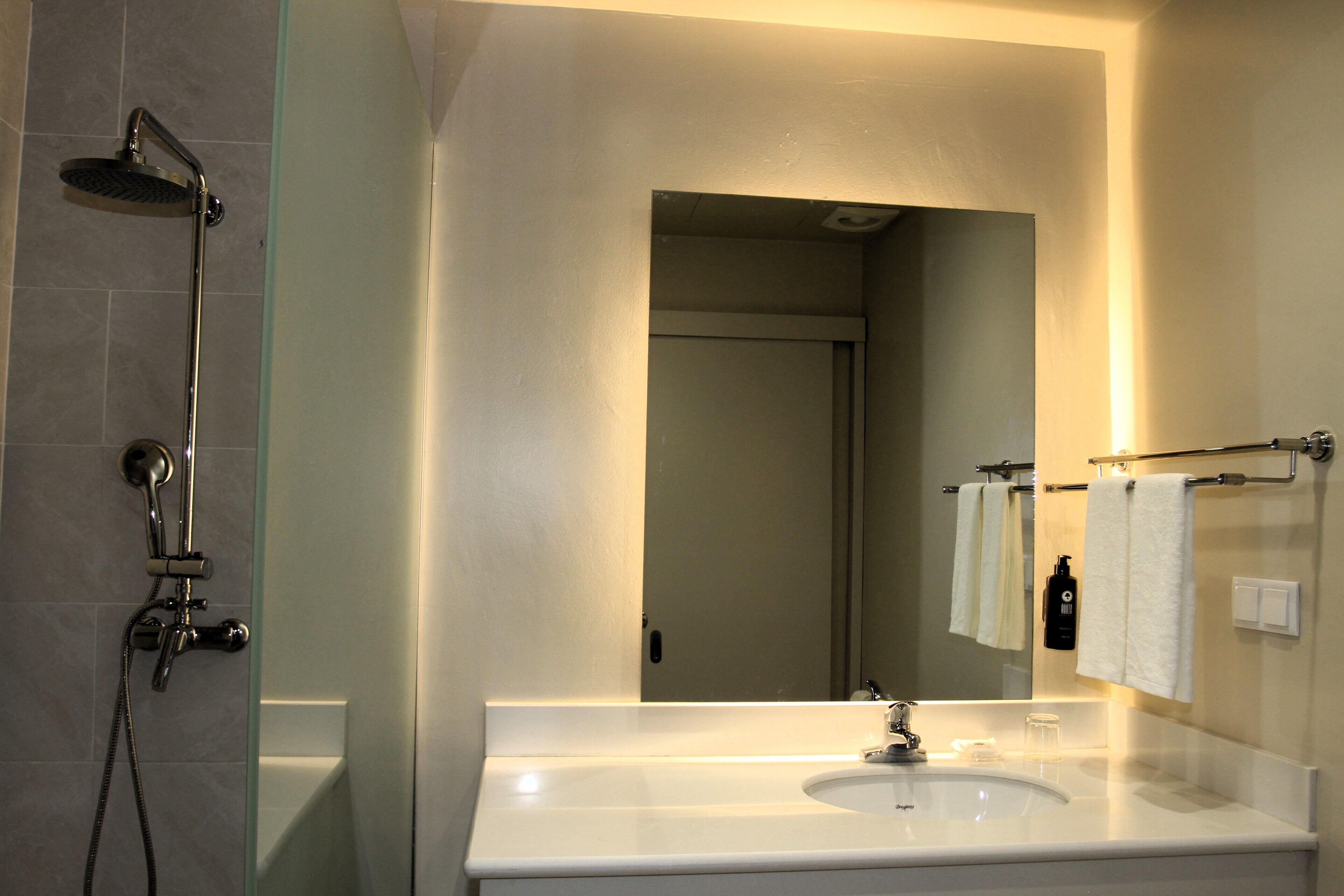 Un baño con ducha de vidrio, lavamanos blanco y espejo.