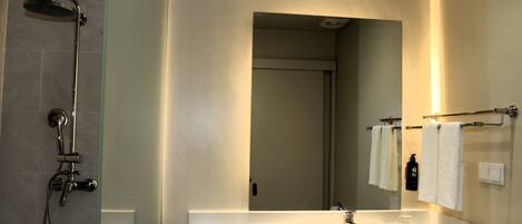 Une salle de bain avec une douche à parois de verre, un lavabo blanc et un miroir.