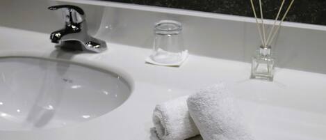 Un lavamanos con grifo, un tarro de vidrio y una pequeña botella de vidrio con ramitas de junco.