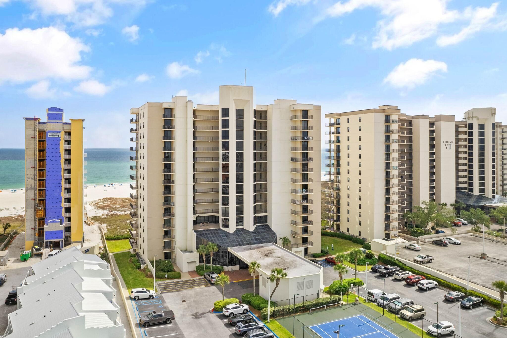 Un grand hôtel avec de nombreux étages, un parking et une vue sur la plage.