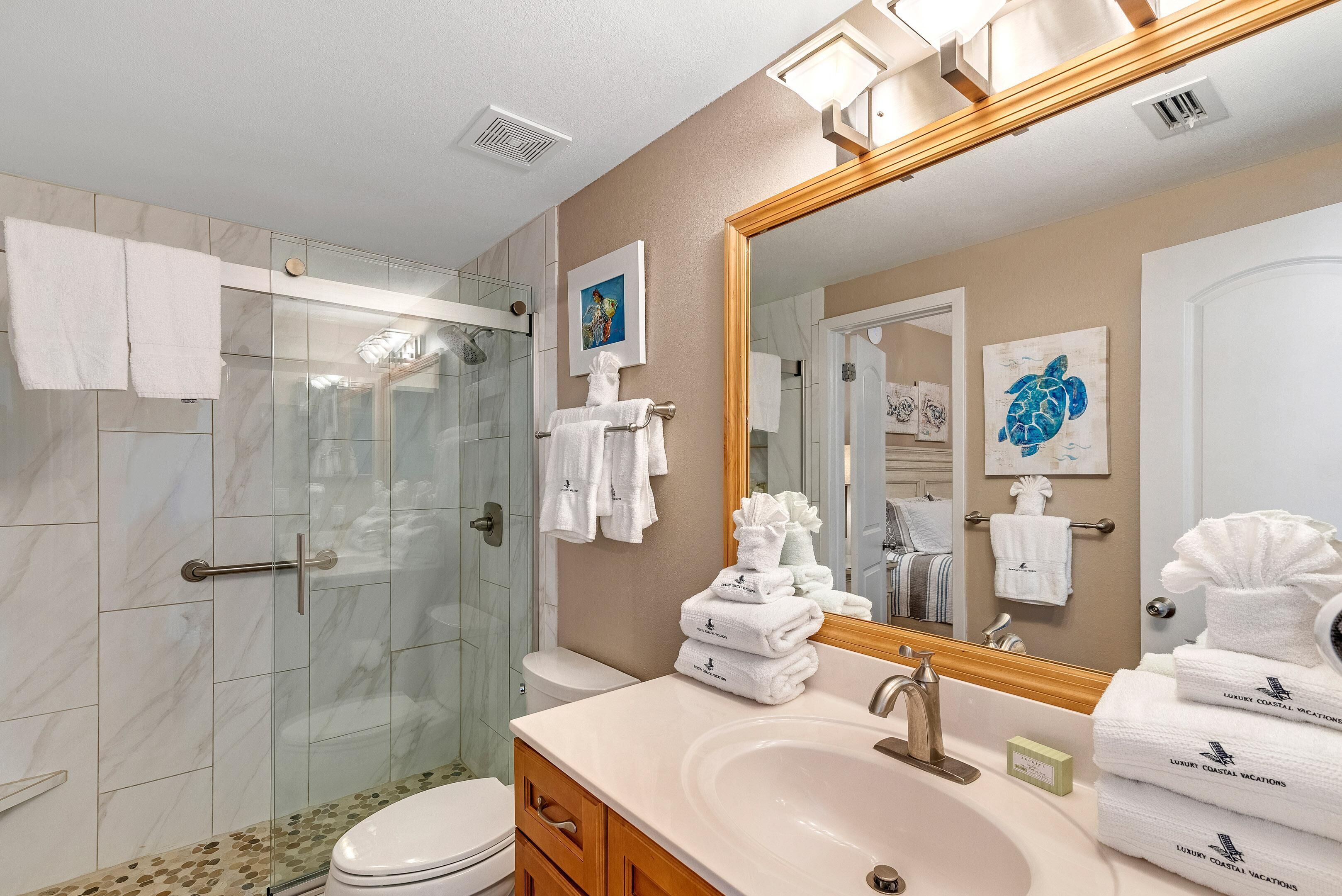 Un baño moderno con cabina de ducha de vidrio, tocador con lavabo y un espejo grande.