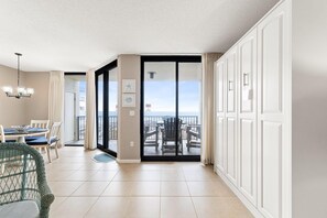 A modern hotel room with a balcony, a dining area with a table and chairs, and a view of the ocean. - Phoenix 8 305 (Orange Beach)