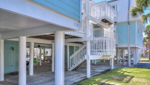 A multi-level wooden deck with railings, columns, and a staircase leading to an upper level. - Boardwalk F3 (Pensacola Beach)