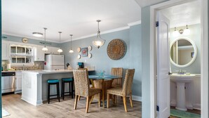 A kitchen with a central island, bar stools, and pendant lighting. - Boardwalk F3 (Pensacola Beach)