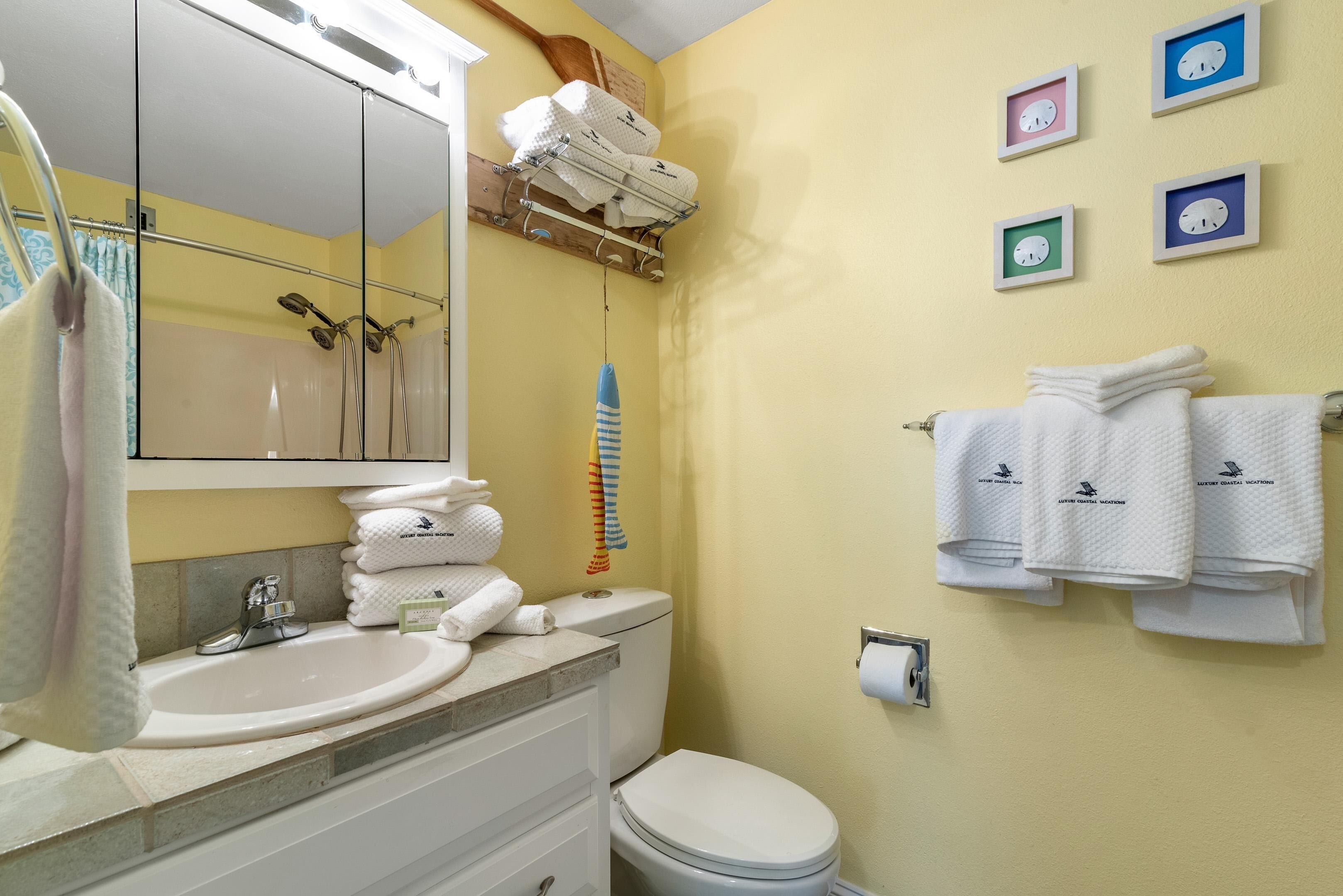 Une salle de bain équipée d’un lavabo, d’un miroir, de toilettes et de serviettes rangées sur un porte-serviettes.