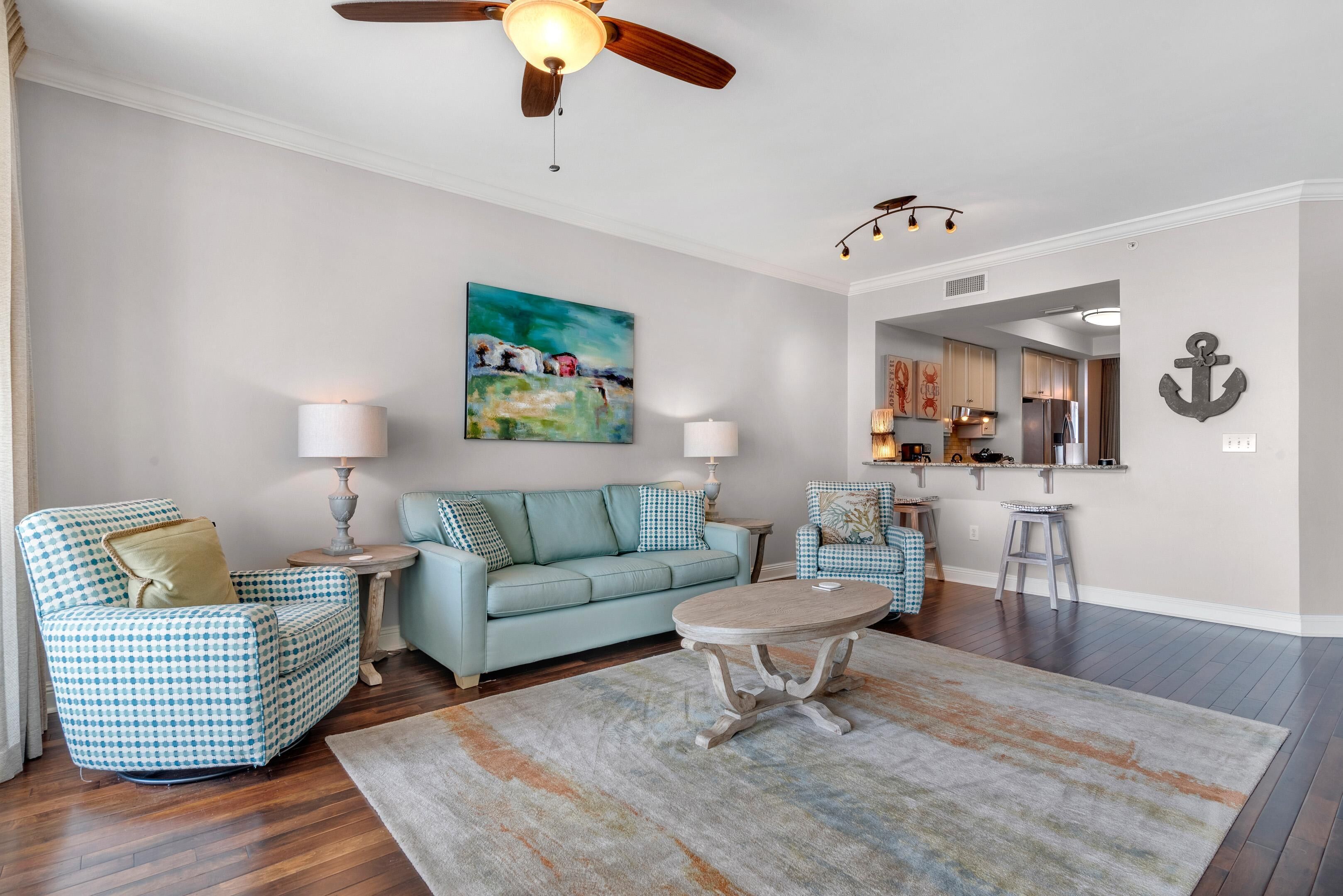 A living room with a sofa, armchairs, a coffee table, and a painting on the wall.