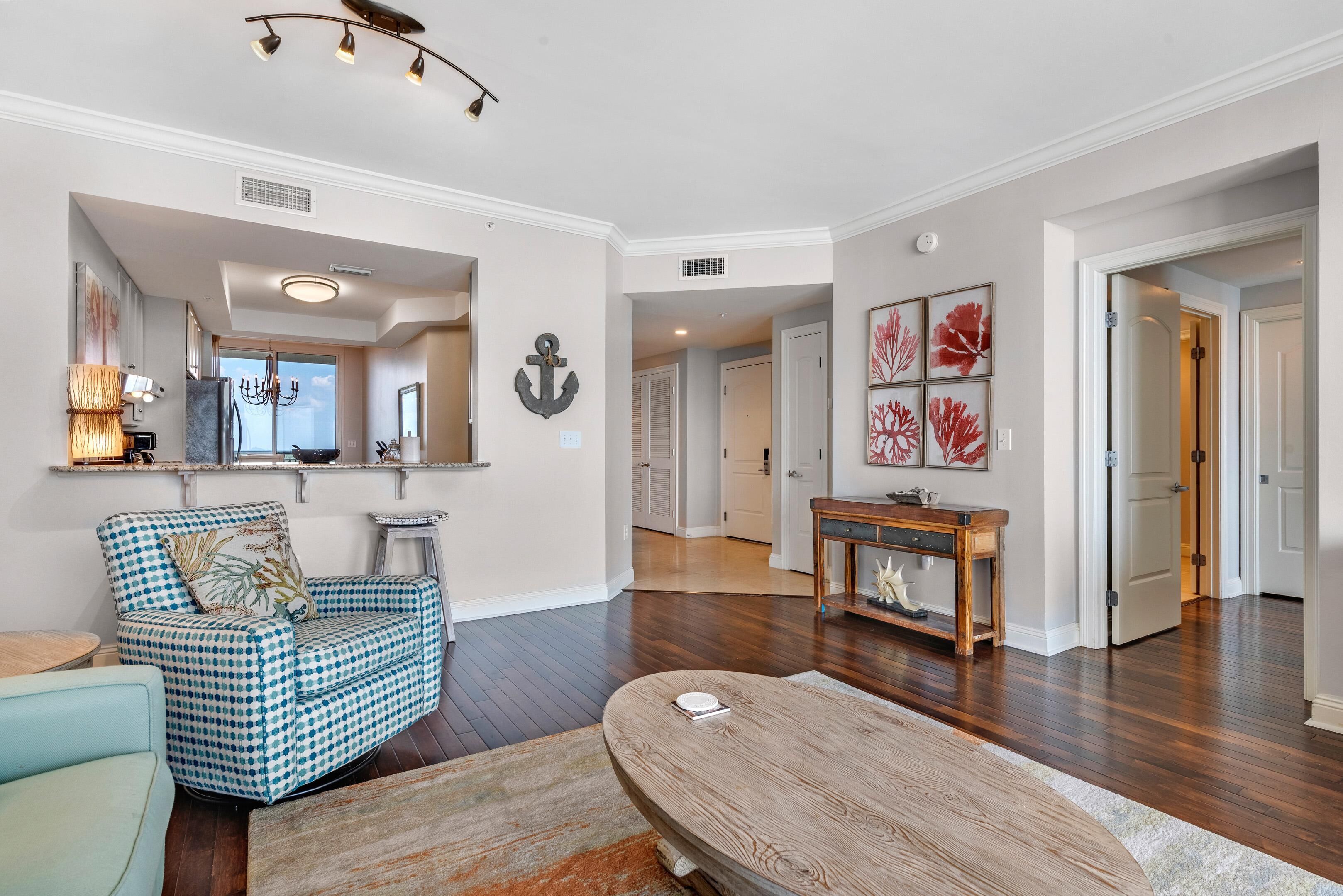 A spacious living room with a checkered armchair, a wooden coffee table, and a chandelier.