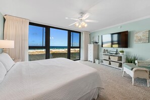 Ein Schlafzimmer mit einem großen Bett, einem Deckenventilator, einem Fernseher und Blick auf den Strand.