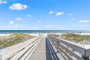 A wooden boardwalk leading to a beach with sand dunes and a clear blue sky. - Seaspray East 1023- Gulf Front (Pensacola)