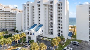 A multi-story hotel with balconies, a parking area, and a view of the ocean. - Seaspray East 1023- Gulf Front (Pensacola)