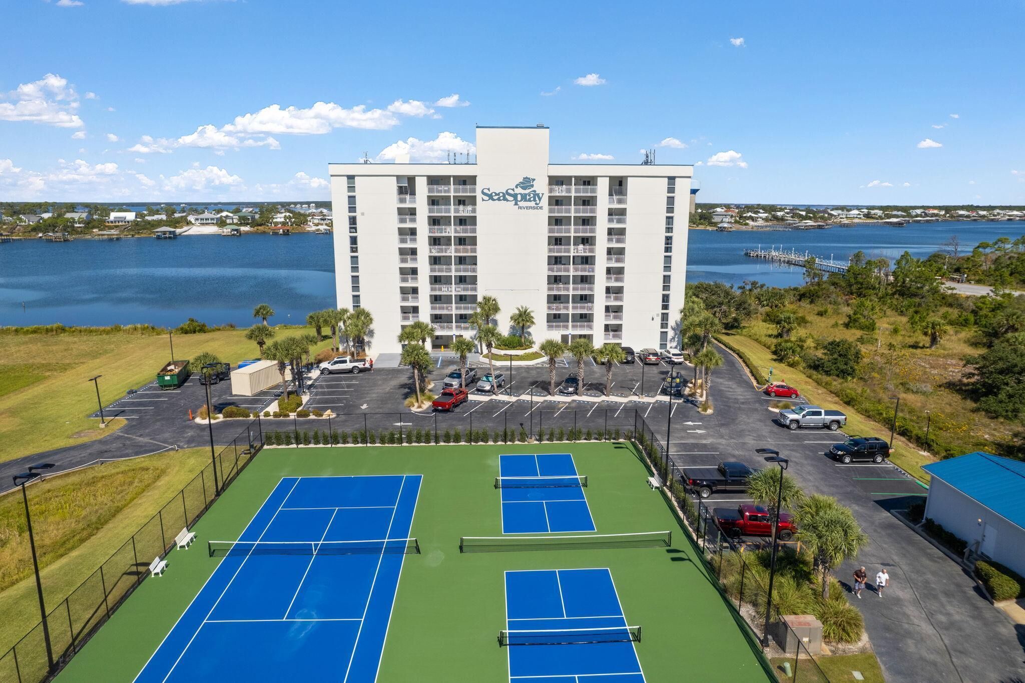 Un hotel con cancha de tenis y estacionamiento.