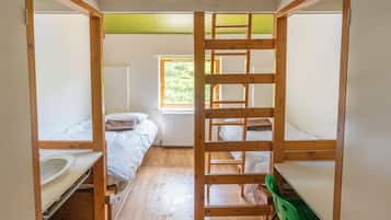 Un dormitorio con literas, una ventana, un radiador y una silla verde.