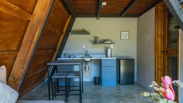 A kitchen with a dining area, a small refrigerator, and a sink.