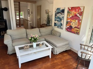 A living room with a sectional sofa, a white coffee table with decorative items, and two fish-themed paintings on the wall.