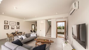 Ein modernes Wohnzimmer mit Sofa, Couchtisch und Fernseher. Eine Treppe führt zu einer weiteren Ebene.