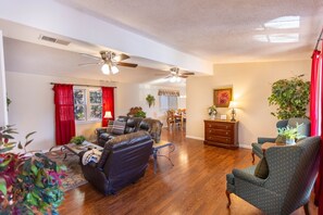 A spacious living room with a fireplace, a dining area, and a kitchen in the background.