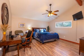 A bedroom with a bed, desk, chair, ceiling fan, TV, and window. - Wimberley Getaway with Private Pool and Fire Pit (Wimberley)