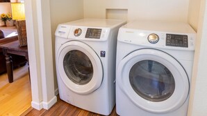 A laundry area with two white front-loading washing machines and wooden cabinets above.
