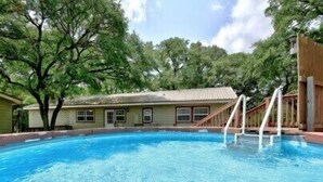 A swimming pool with a wooden deck and a house in the background.
