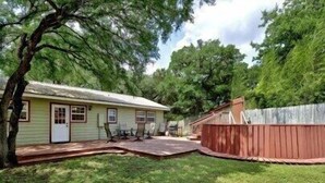 A residential property with a house, a fenced yard, and a tree.