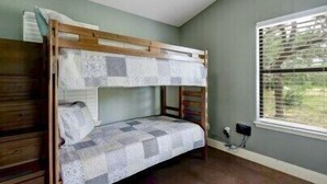 A bunk bed with a checkered bedspread, a ceiling fan, and a window with blinds.