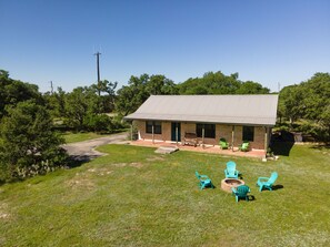 A small house with a porch, outdoor seating, and a fire pit. - Star Ranch Cottage- Starry Nights & Cozy Comfort (Wimberley)