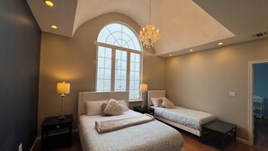 A bedroom with two beds, a chandelier, and a large window. - Beach Mansion • 1 Block to Beach • Sleeps 16+ • Large Groups & Family Trips (Keansburg)