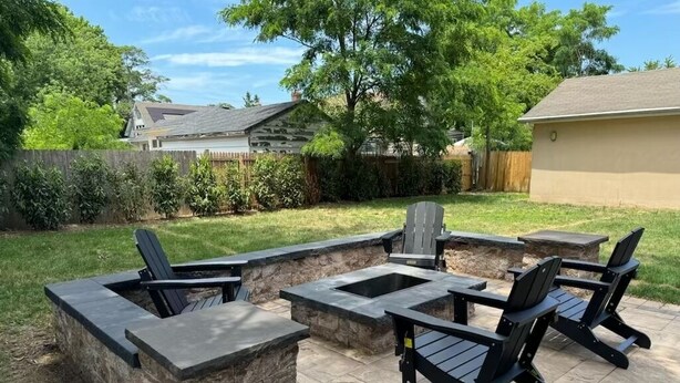 An outdoor patio with stone planters, black Adirondack chairs, and a fire pit. - Beach Mansion • 1 Block to Beach • Sleeps 16+ • Large Groups & Family Trips (Keansburg)