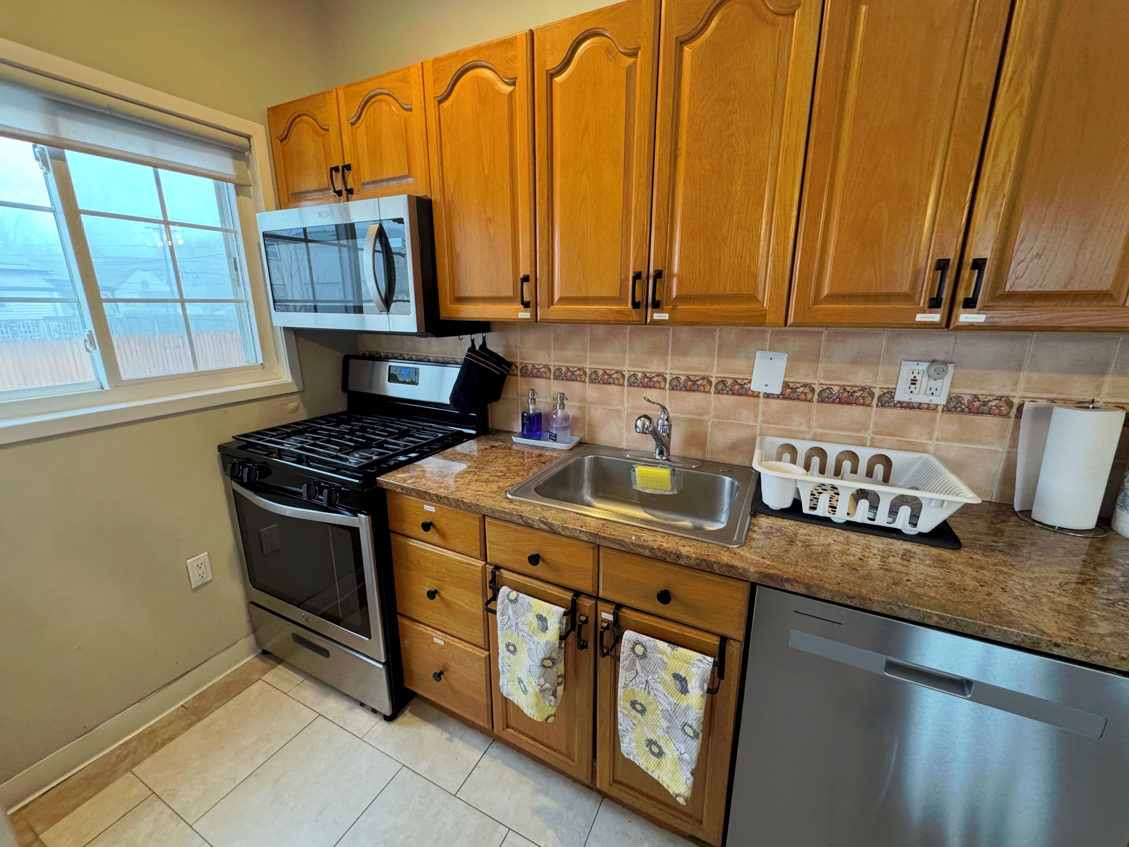 A kitchen with wooden cabinets, a stove, a sink, and a dishwasher.
