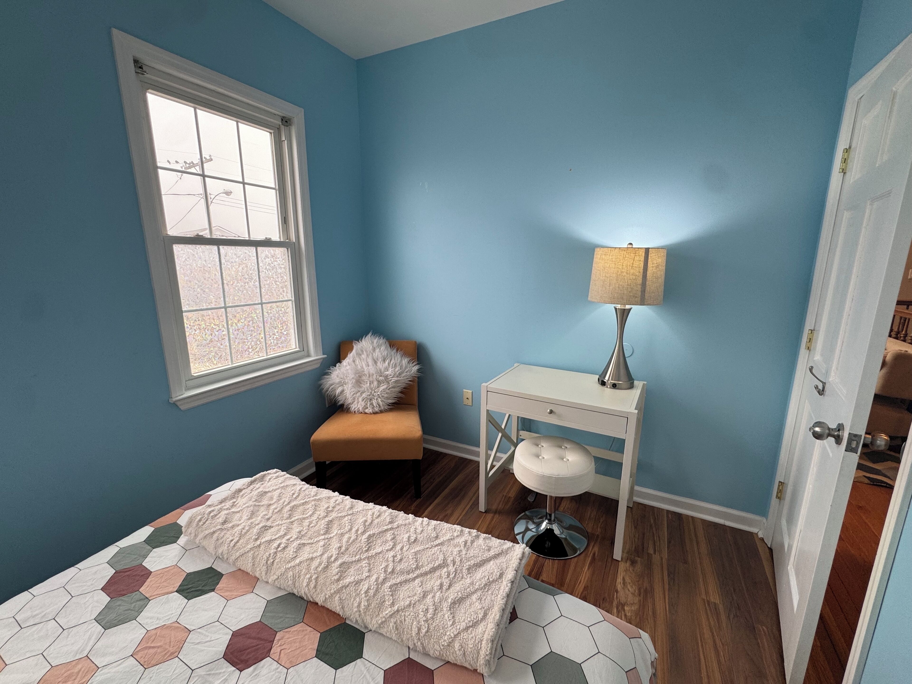 Une chambre à coucher avec un lit, une chaise, un bureau et une lampe.