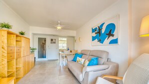 Ein geräumiger Wohnbereich mit einer Couch, Holzregalen und einem Deckenventilator.