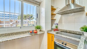 Eine Küche mit großem Fenster, Granit-Arbeitsplatten, einer Edelstahl-Dunstabzugshaube und einem Einbauofen.