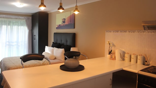 A hotel room with a bed, a desk, a chair, a lamp, a picture on the wall, and a window with curtains.