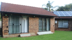 A single-story house with a brick exterior, a tiled roof, and a small front yard.