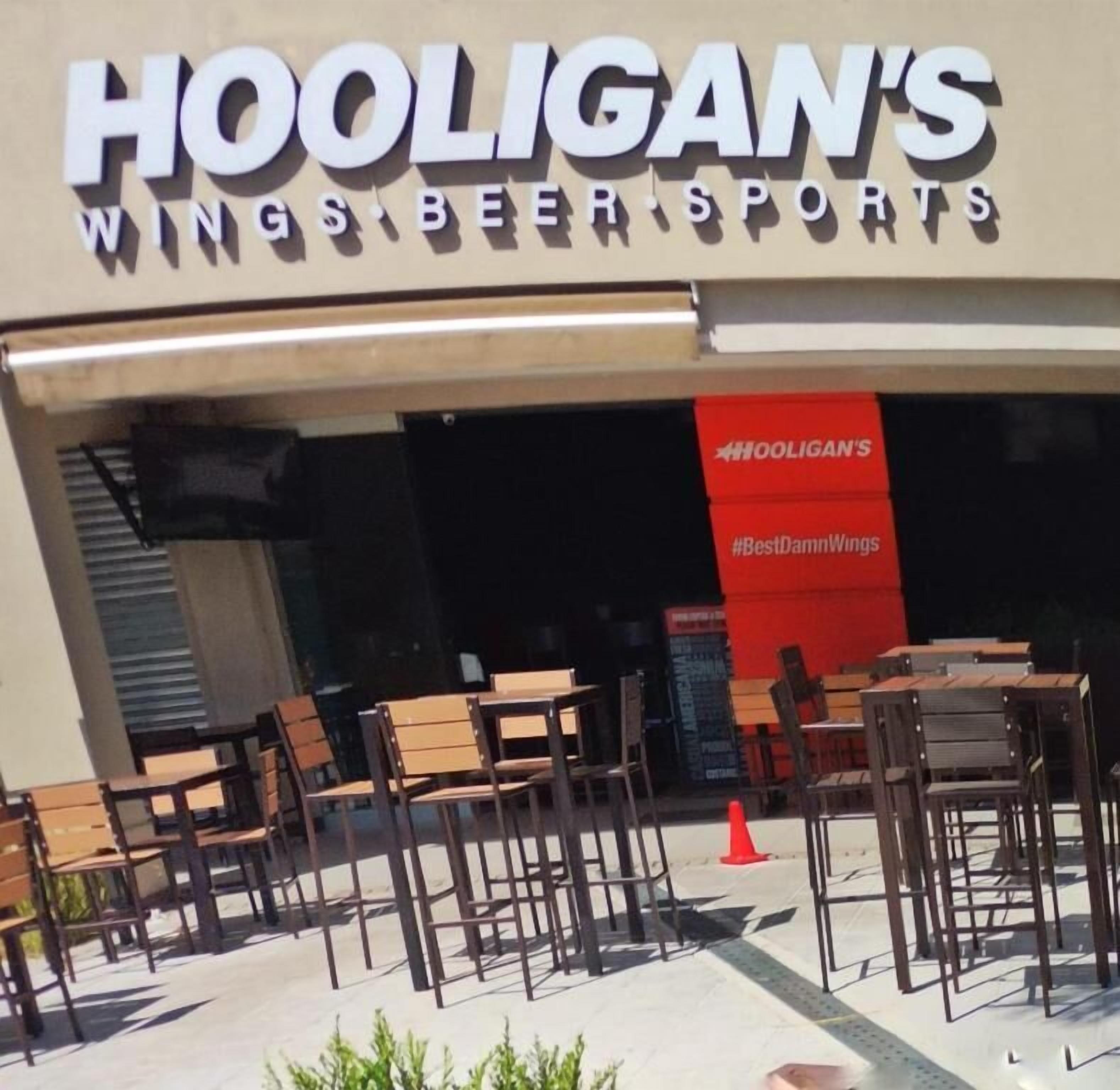 The exterior of Hooligan's Wings Beer Sports with outdoor seating and a red banner.