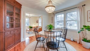 A dining area with a round table, chairs, and a chandelier. There is a wooden cabinet with glass doors and a potted plant on the table. - Charming Virginia Retreat w/ Covered Porch & Yard! (Farmville)