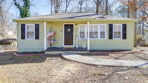 A single-story house with a front porch, a welcome sign, and a small garden area. - Pet-Friendly Georgia Retreat w/ Fire Pit & Porch! (Forest Park)