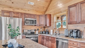 Una cocina con armarios de madera, electrodomésticos de acero inoxidable, encimeras de granito y una ventana con vistas.