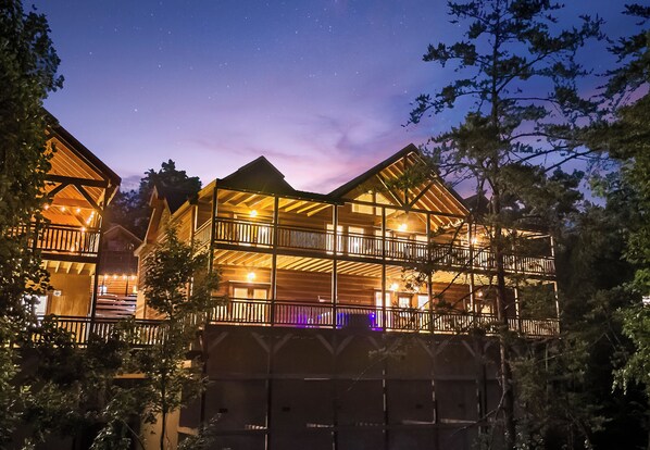 A multi-story wooden building with balconies, surrounded by trees.
