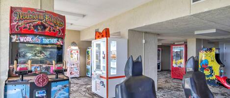 A gaming arcade with various machines, including a 'Deadstorm Pirates' game, and two gaming chairs.
