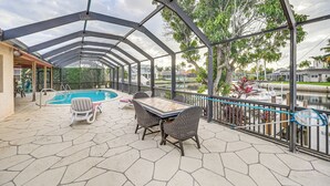 A covered outdoor area with a pool, lounge chairs, and a table. - Marco Island Home w/ Private Pool & Water Views! (Marco Island)