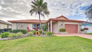 A single-story house with a red-tiled roof, stone facade, and a red garage door. - Marco Island Home w/ Private Pool & Water Views! (Marco Island)