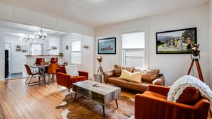 Un salón amplio con comedor, un sofá de cuero marrón y una mesa de centro moderna.