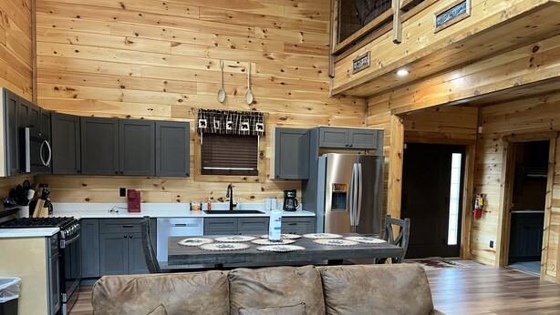 Interior acogedor de una cabaña con comedor, cocina y un sofá de cuero.